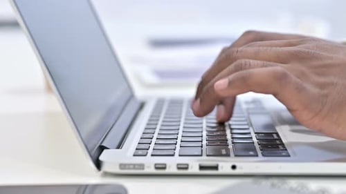 Nahaufnahme der Hände eines afrikanischen Mannes, der auf Laptop tippt