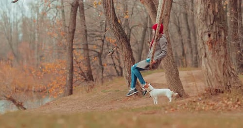 Woman Swings with Dog in Autumn Park