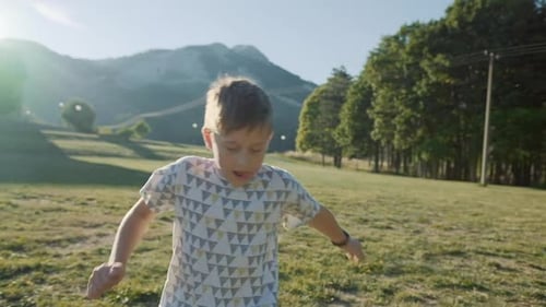 8 years old boy plays soccer on the field at sunset