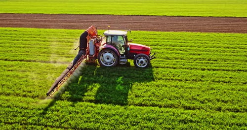 Traktor mit Pestizidtank sprüht Ernte auf Feld