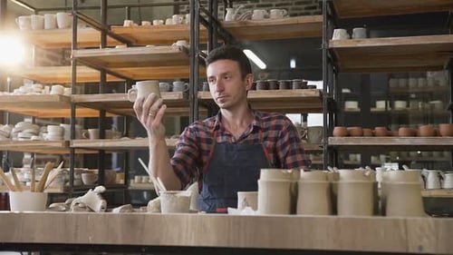 Potter Inspecting Ceramic Mug in Pottery Studio