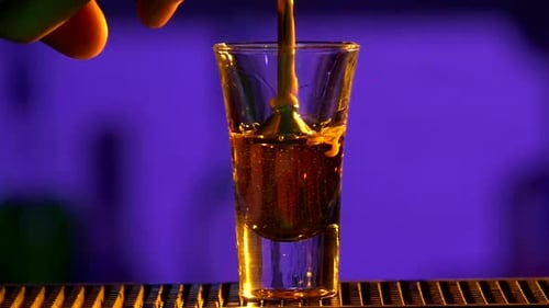 Barkeeper gießt weiterhin einen Cocktail in ein Glas mit spezieller Ausrüstung, Schüssen, Zeitlupe