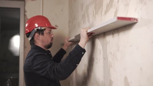 Construction Worker Using Level on Wall Renovation