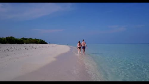 Family of two sunbathe on marine island beach holiday by aqua blue sea and white sandy background of
