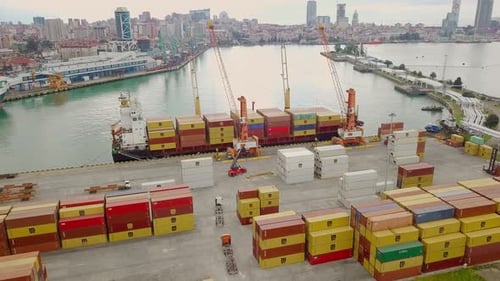 Schiffsansicht von einer Drohne aus. Entladen von Containern durch eine Crew und einen Kran im Hafen
