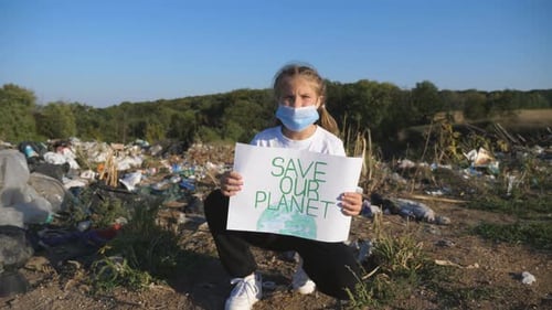 Child Holding Save Our Planet Sign at Landfill