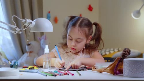 Focused Cute Preschooler Girl Doing Crafts at Home at the Desk