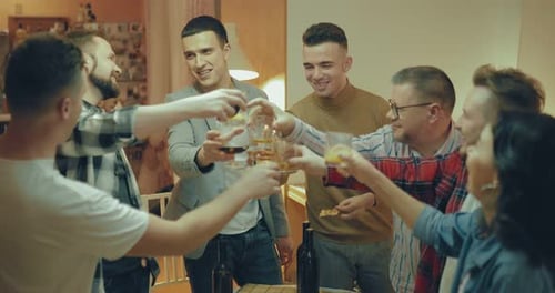 Merry Company Celebrates a Holiday at Home with Friends. Men and Women Laugh and Check Their Glasses