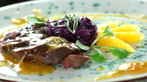 Gourmet Meat Dish with Orange Segments and Red Cabbage
