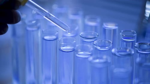 Close Up of Pipette Dripping Liquid into Test Tubes