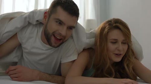 Romantic Couple Cuddling and Kissing Under White Blanket