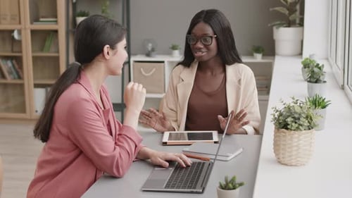 Two Mixed-race Businesswomen Talking in Office