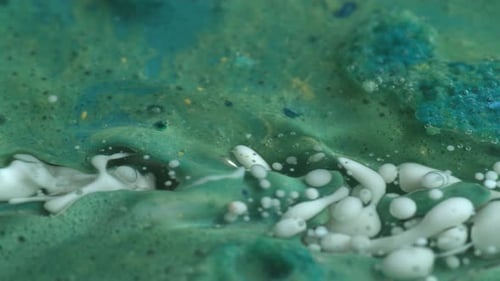 Abstract close up texture of oil with green and white paint, slow motion.