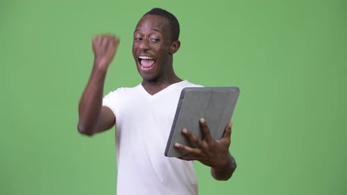 Man Celebrating Success Using Tablet in Front of Green Screen