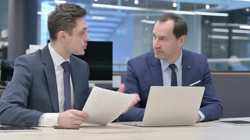 Two Businessman Discussing While Working on Laptop in Office