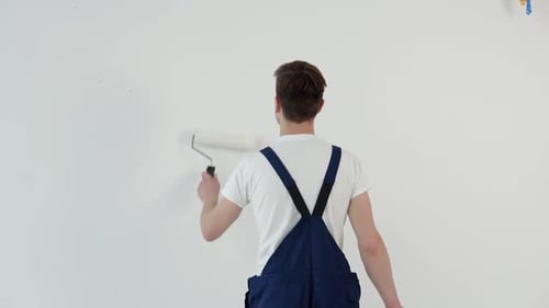 Maler mit einer Walze in den Händen malt eine weiße Wand
