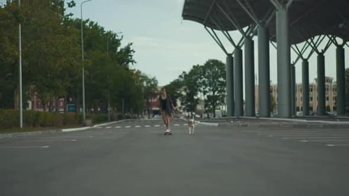 Young Beautiful Woman Riding on Skateboard or Longboard on the Street with Her Husky Dog