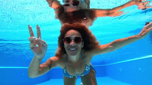 Young adult woman have fun and enjoy blue pool water in summer holiday vacation