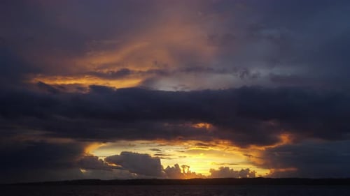 Majestic Timelapse of Serene Sea and Orange Skies Filled with Clouds