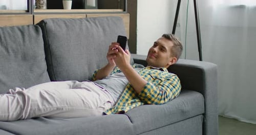Young Man Is Texting on His Smartphone