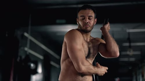 A Muscular Sportsman is Doing Exercise in the Gym