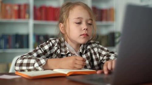 Closeup Portrait of Focused Primary Child School Girl Doing Homework Writing Notes in Paper Notebook