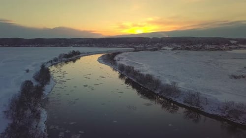 Amazing winter landscape with red sunrise. Drone flying over the river