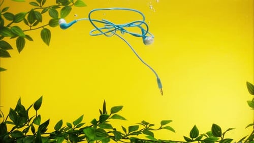 Auriculares azules hundiéndose en el agua sobre fondo amarillo, primer plano arrojar auriculares con cable a un río