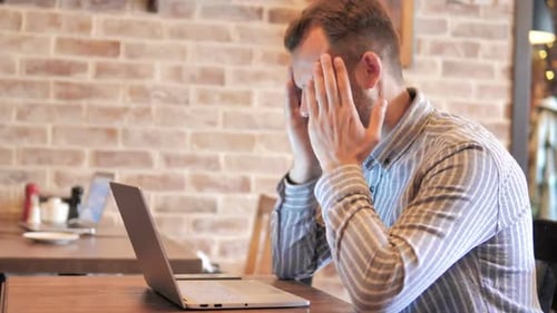 Man Frustrated By Results on Laptop in Loft Place