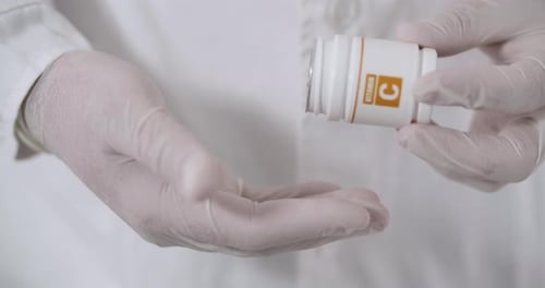 Vitamin C Pills Poured into a Gloved Hand