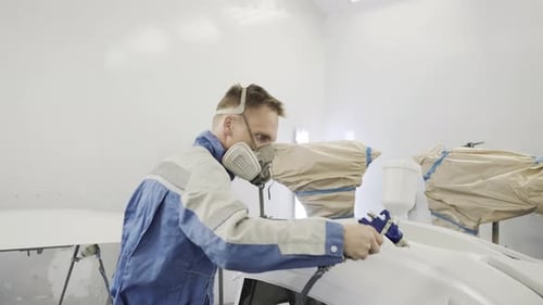 Automotive Technician Spray Painting Car Parts in Workshop