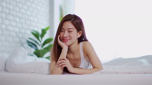 Smiling Woman Relaxing Peacefully on Bed in Bedroom
