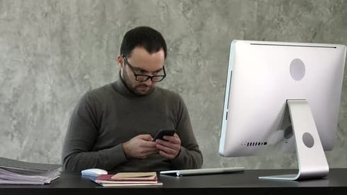 Bearded Young Businessman Working at Modern Office. Man Looking in His Smartphone and Typing