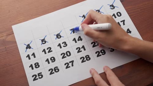 The Hand Crosses Out the Days in the Calendar with a Blue Marker