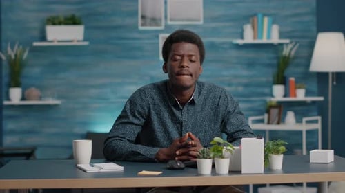 Young Adult Sits at Desk with Plants