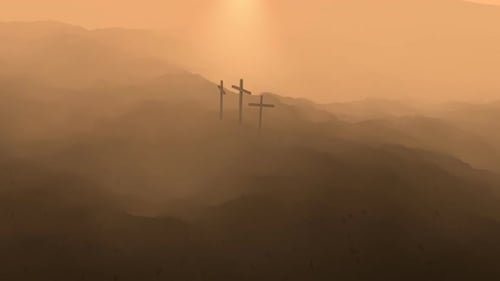 Atmospheric, dark image of three crosses silhouetted on the top of a mountain.
