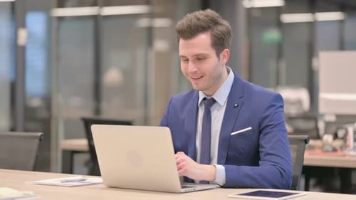 Businessman Talking on Video Call on Laptop in Office