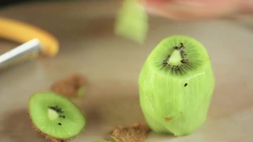 Hands Peeling and Slicing a Kiwi Fruit