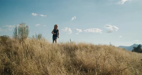 Carefree children run on the mountain field at summer travel at vacations