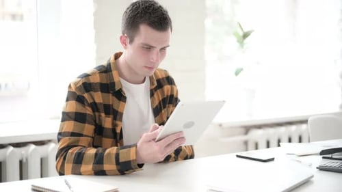Frustrated Young Adult Using Tablet at Desk