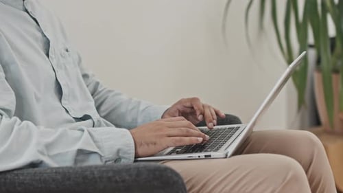 Man Typing on Laptop Computer While Seated Indoors