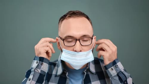 Man Adjusting a Light Blue Disposable Face Mask