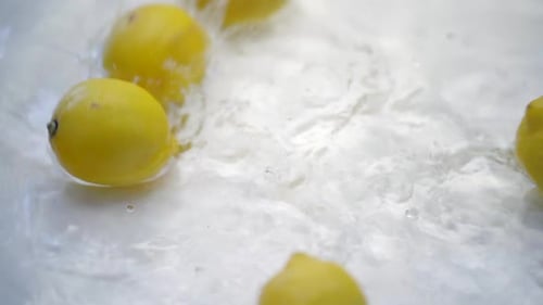 Bright Yellow Lemons Splashing Into Water