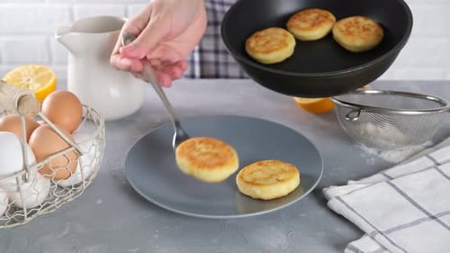 Placing Fresh Pancakes onto a Plate in Kitchen