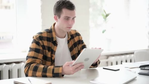 Man Works on Tablet at Bright Desk Indoors