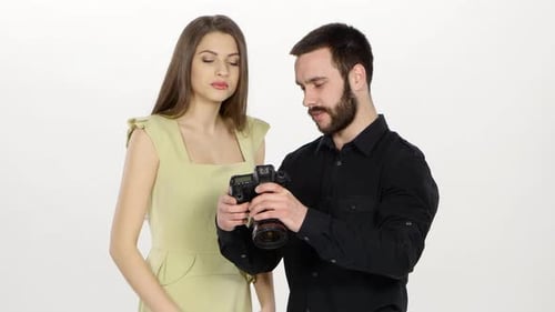 Woman and Man Looking at Photos on Camera