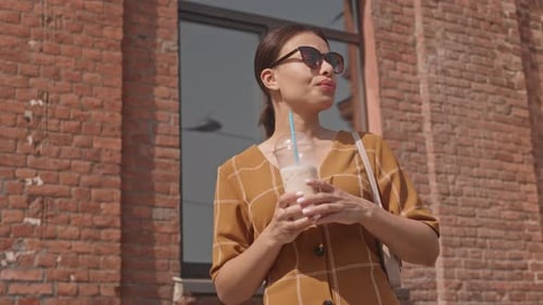 Stylish Woman Drinking Iced Coffee in City