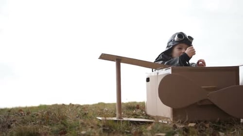 Junger Pilot oder Fliegerjunge spielt und lächelt mit seinem Carboard-Flugzeug Nahaufnahme