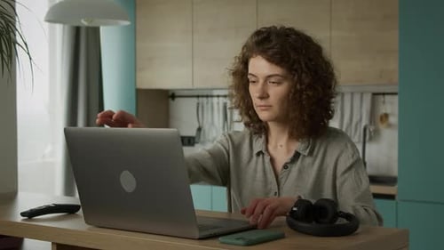Woman Works on Laptop in Home Kitchen