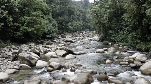 Flying over a beautiful river with large boulders in a tropical forest